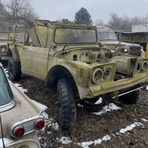 A yellow truck is parked in the dirt.