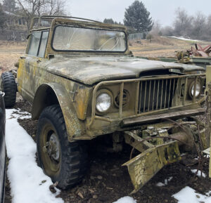 A rusted old jeep is parked in the snow.